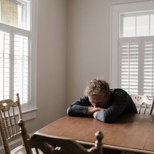 man sitting at table experiencing low mood and depression